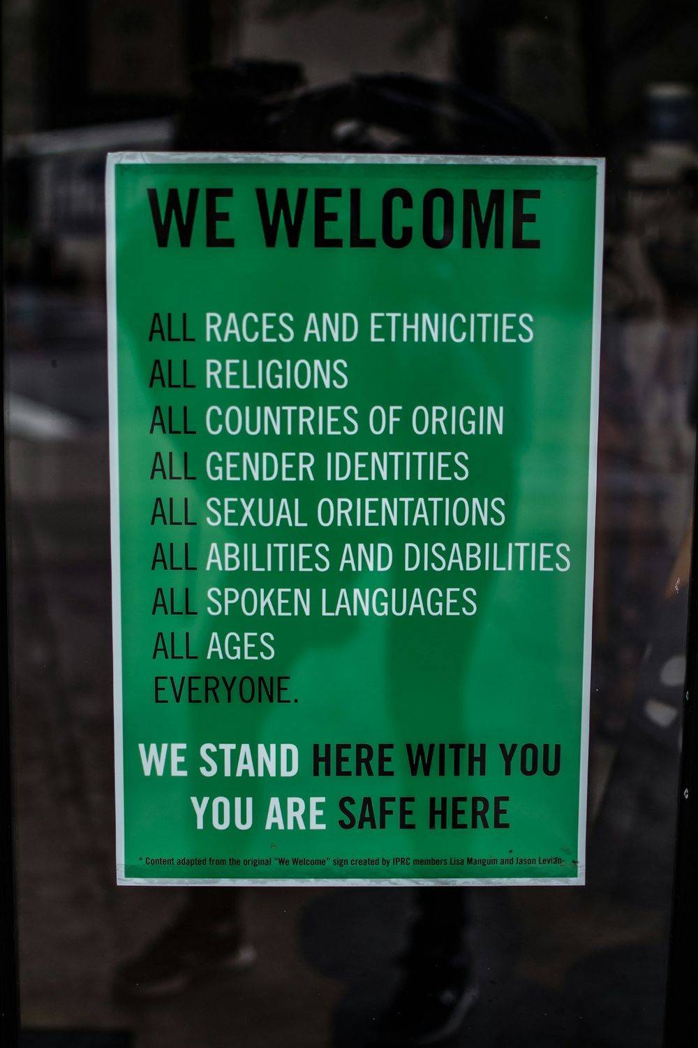 A green “We welcome” sign listing all races, religions, genders, abilities and languages